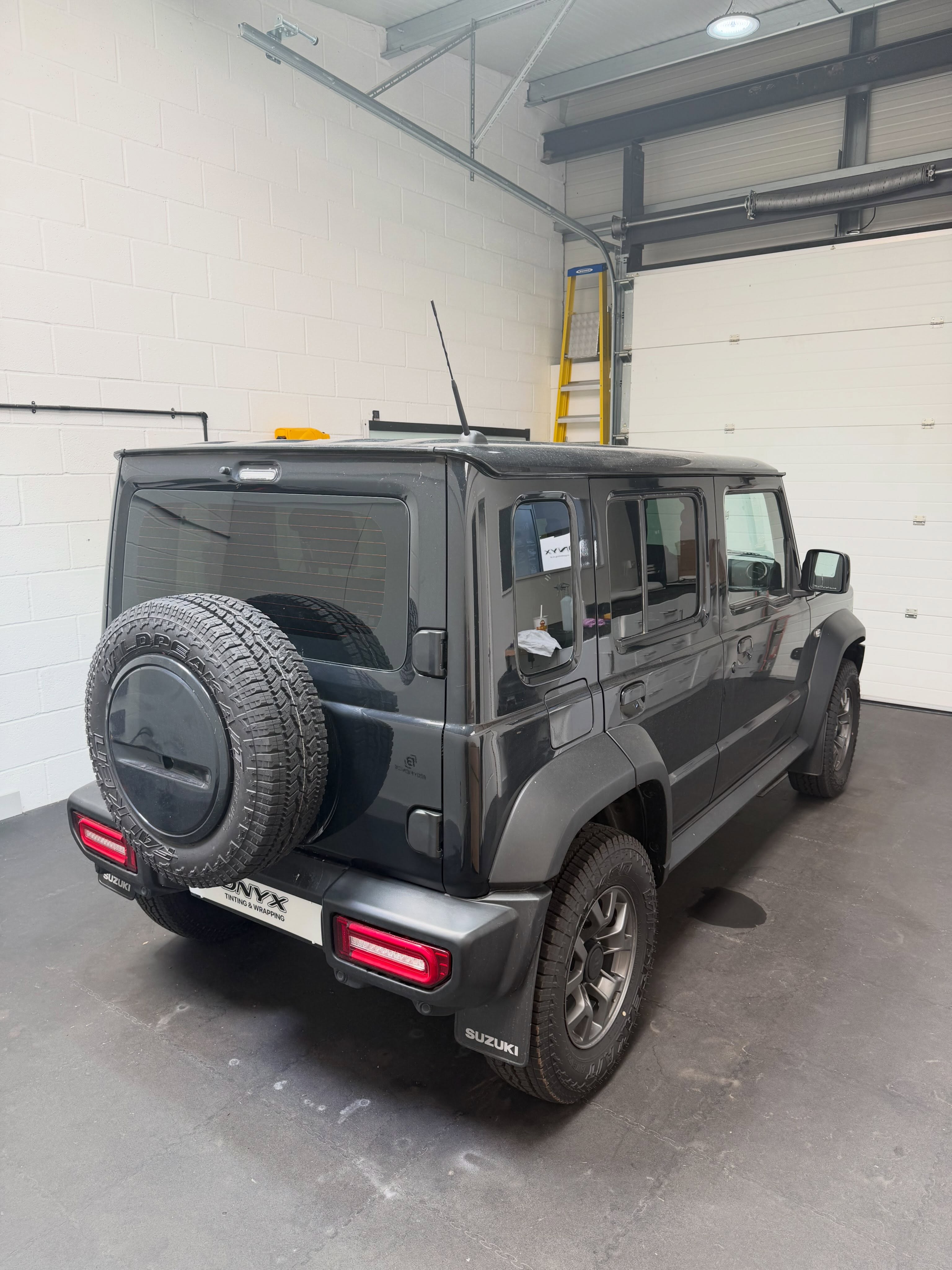Five-door Suzuki Jimny with 15% LLumar rear window tint, viewed from the rear three-quarter angle