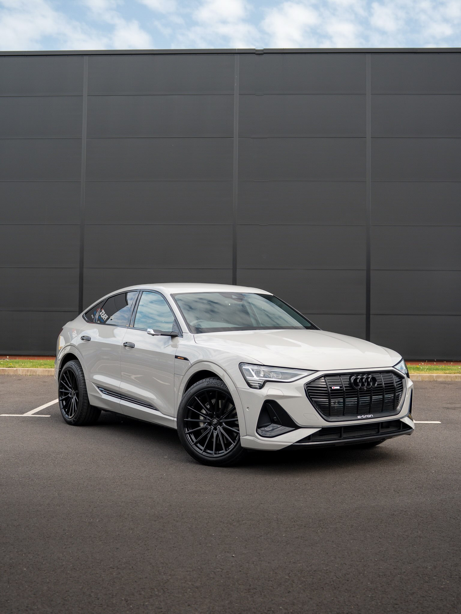 Audi e-tron Sportback 55 quattro in a Crayon grey wrap with black 21-inch Brock B43 wheels, front three-quarter view