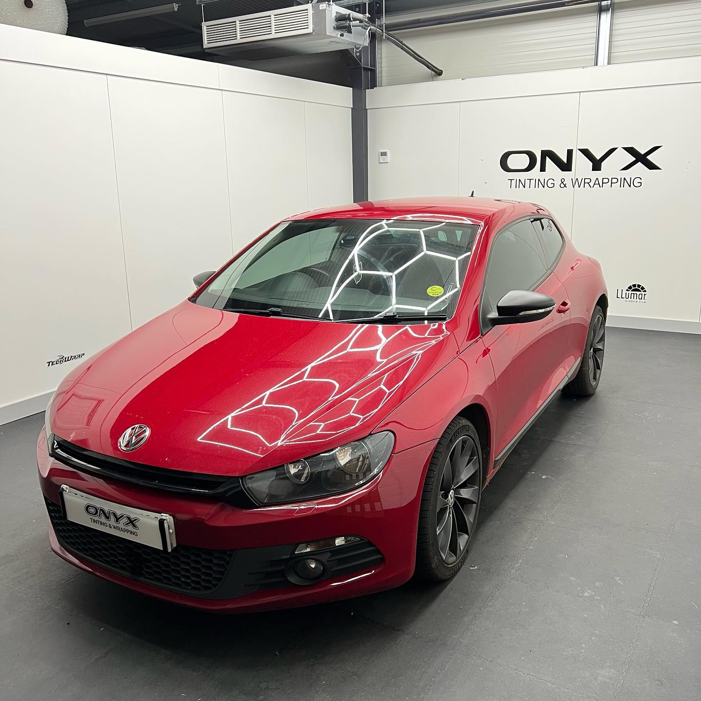 Red Volkswagen Scirocco with matte black mirror caps