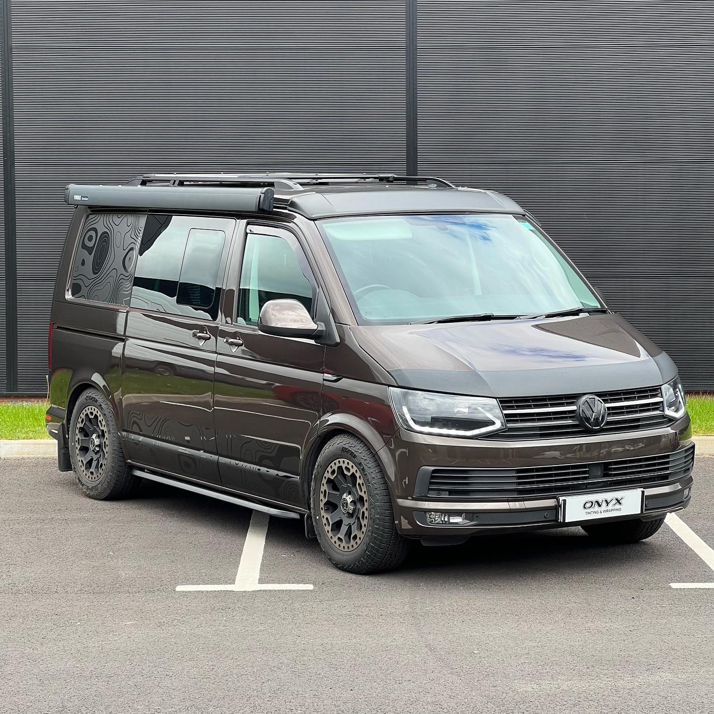 Brown VW Transporter with topographic contour-map graphics on its side panels
