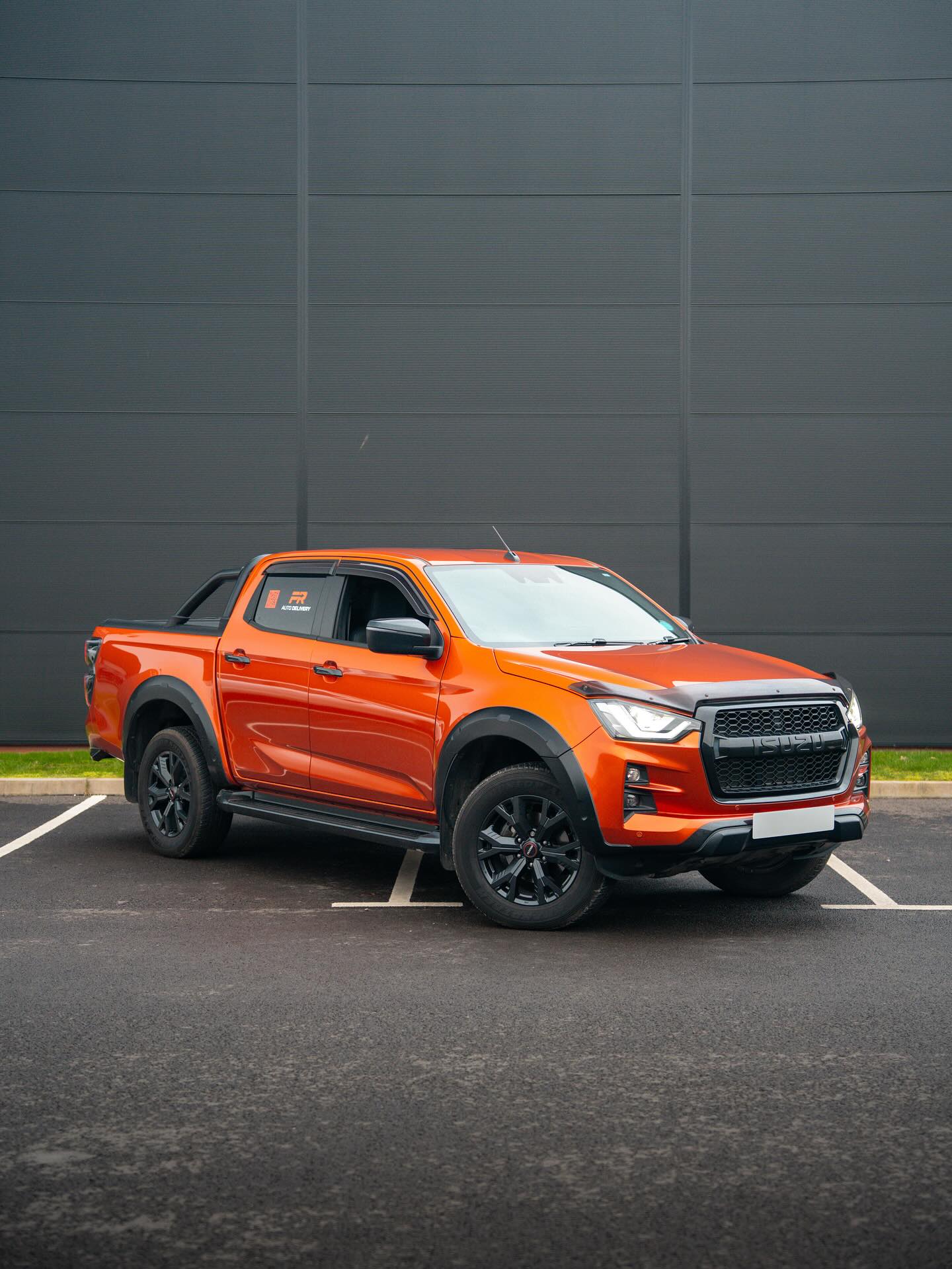 Orange Isuzu pickup with PR Auto Delivery signwriting on its rear side window