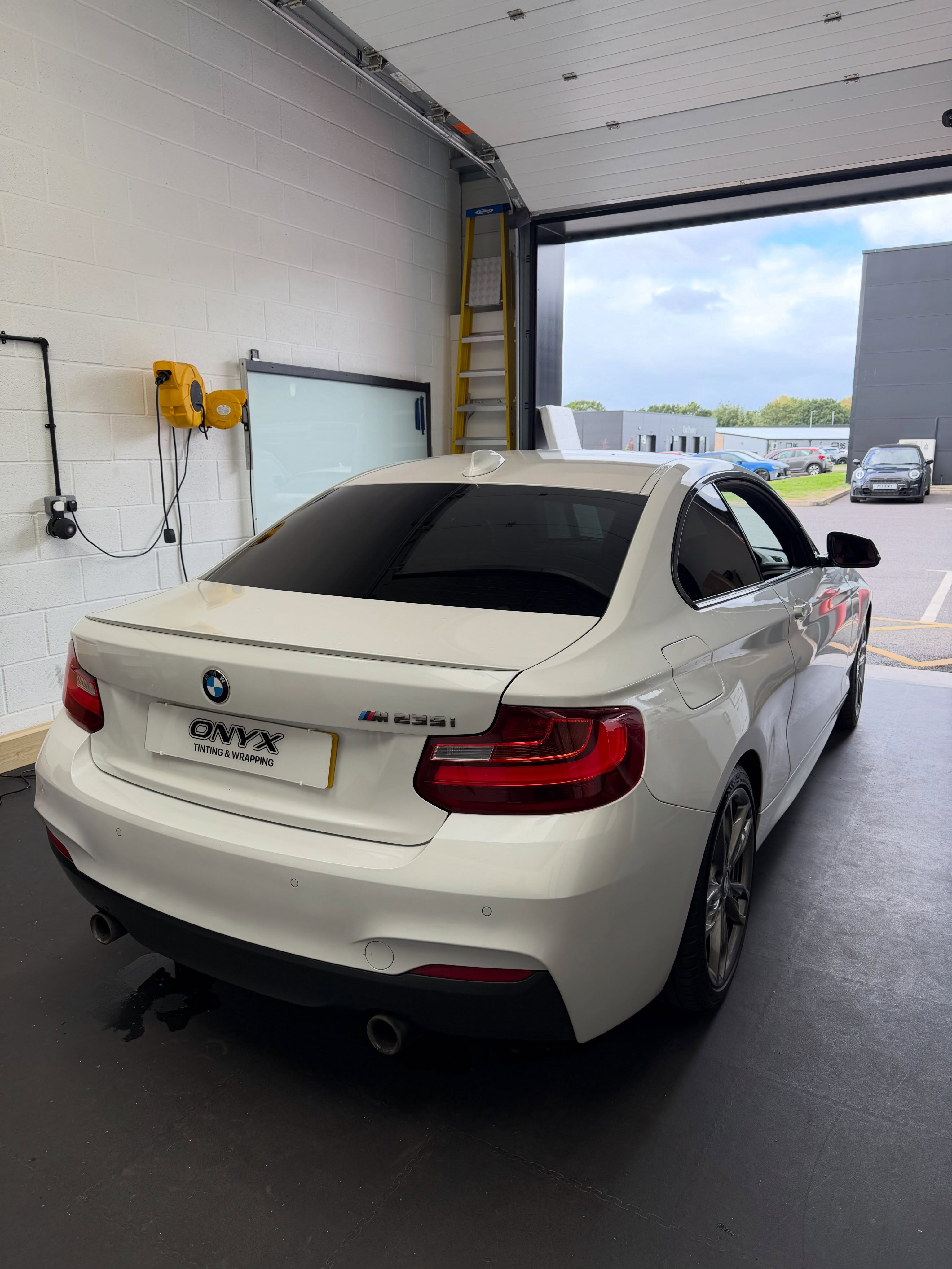 White BMW M235i F22 coupé with 15% LLumar rear window tint, viewed from the rear three-quarter angle